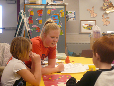 FSU student-athlete Samantha Fordyce plays a word game with two Riverview Elementary School students.  (Photo by Katie Carito)